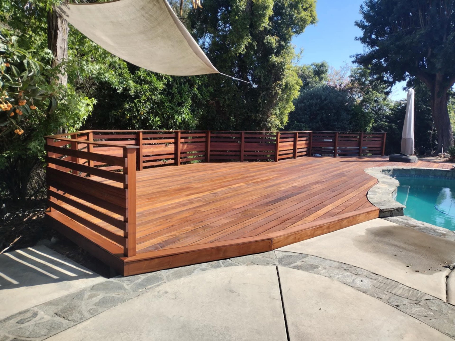 Freshly refinished poolside wood deck with a warm, restored finish